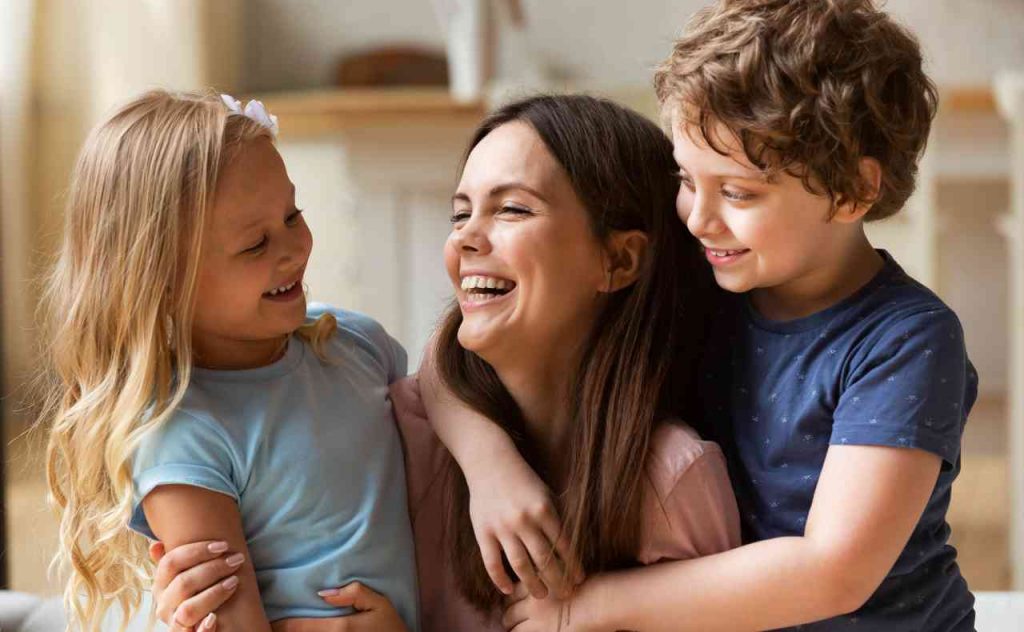 Mamma che ride abbracciando i due suoi figli di circa 8 anni