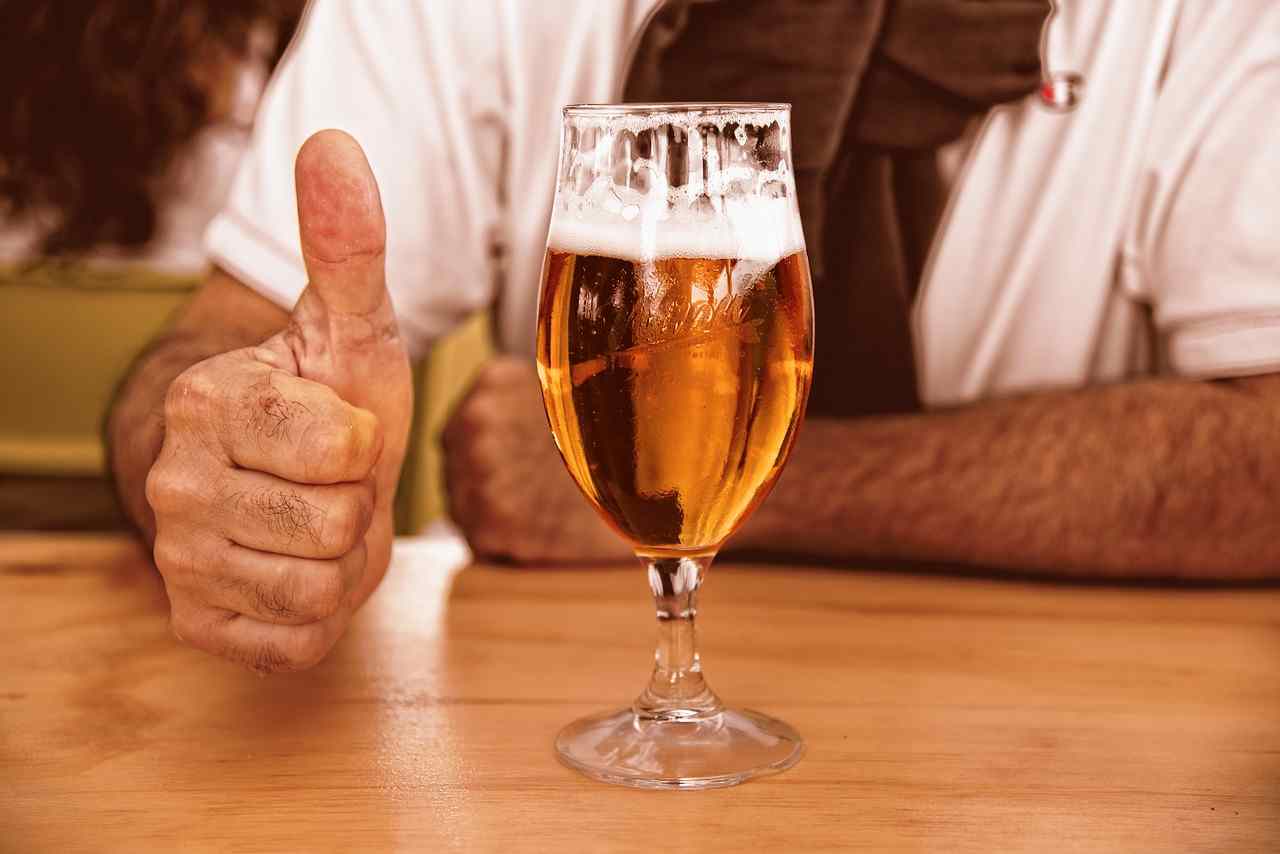 Una birra e una mano con il pollice alzato