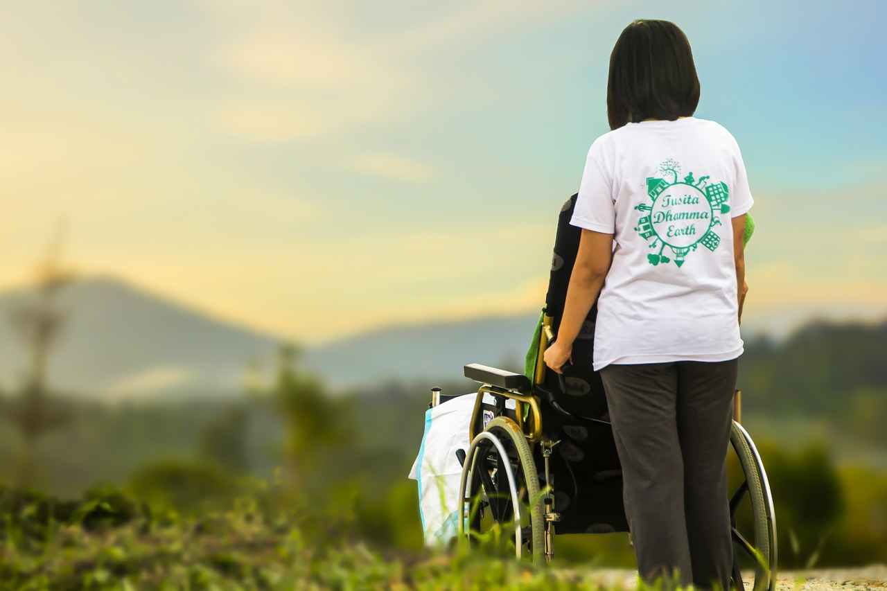 Donna di spalle in piedi con una sedia a rotelle