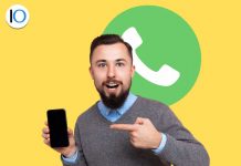 Uomo che indica telefono con logo whatsapp alle spalle