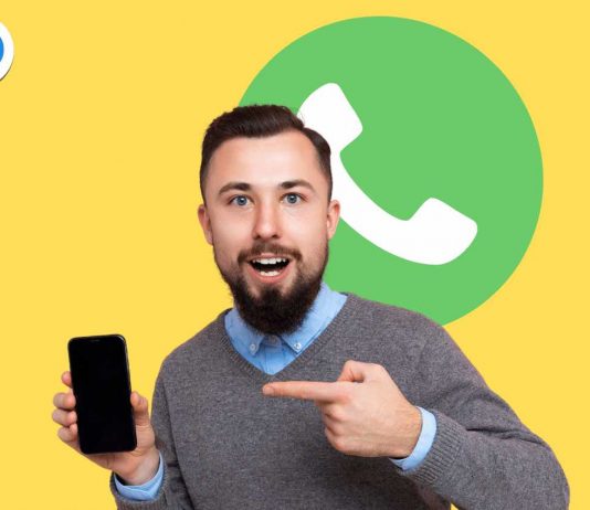 Uomo che indica telefono con logo whatsapp alle spalle