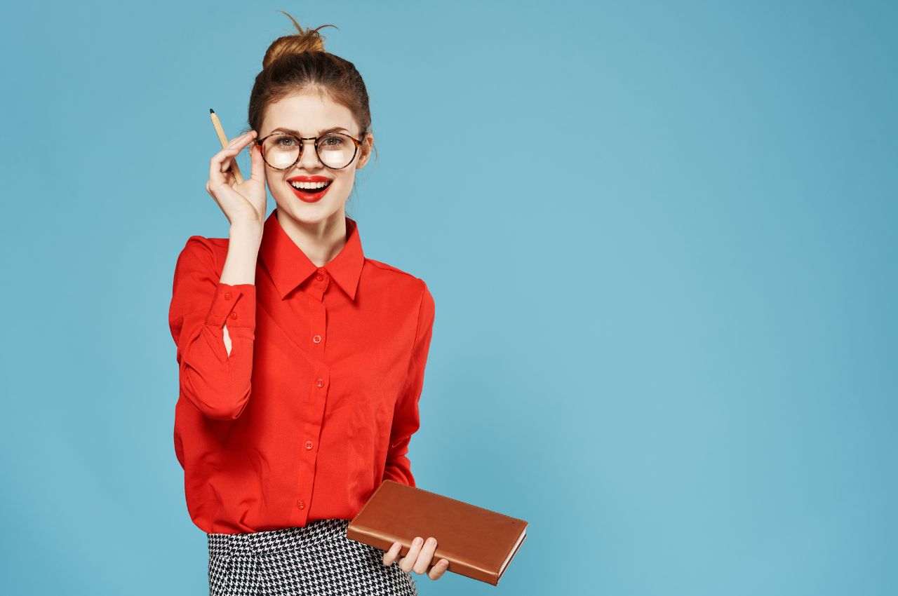 donna sorridente con occhiali, matita e agenda in mano