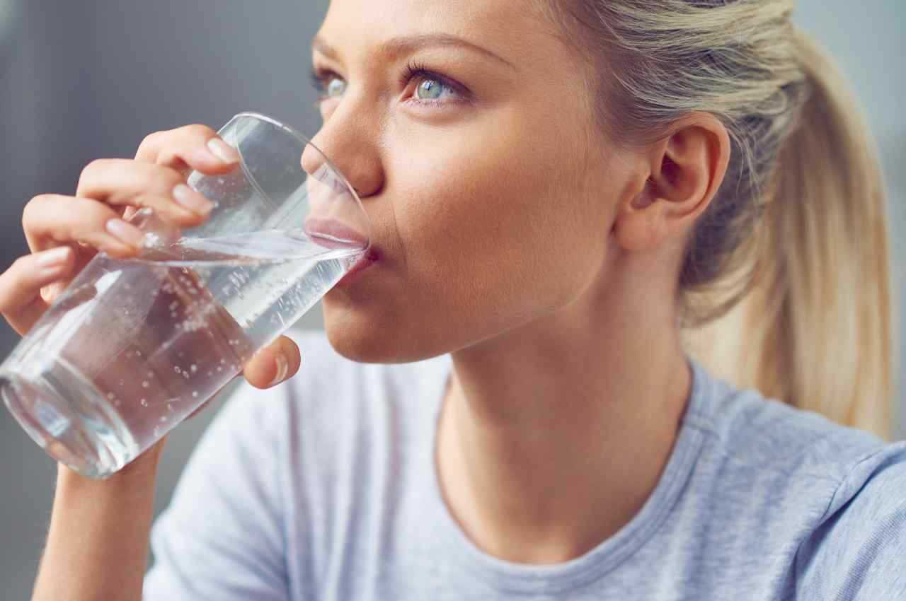 ragazza che beve un bicchiere di acqua