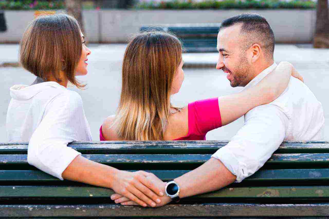 coppia con ragazzo che tiene la mano ad un'altra ragazza. tradimento