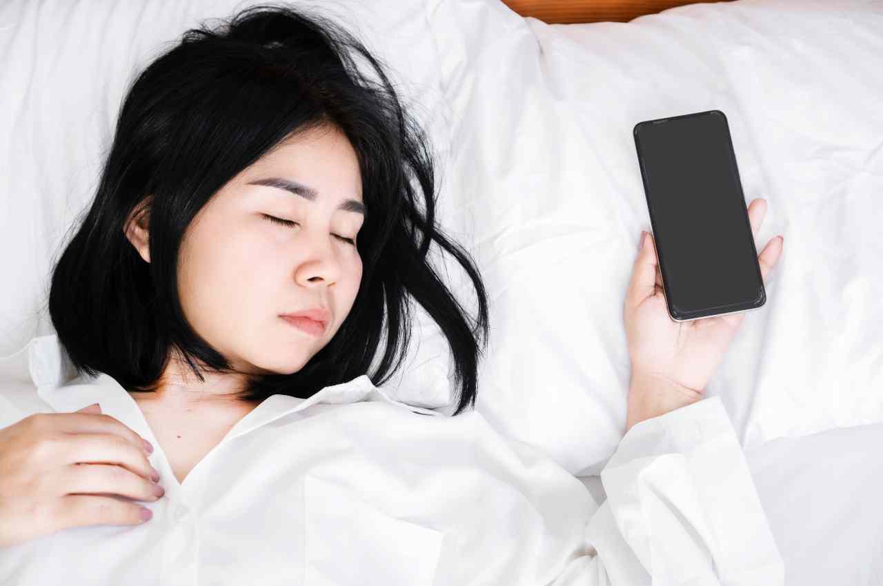 ragazza che dorme con smartphone in mano