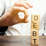 Uomo che cerca di far cadere dei dati con su scritto debit