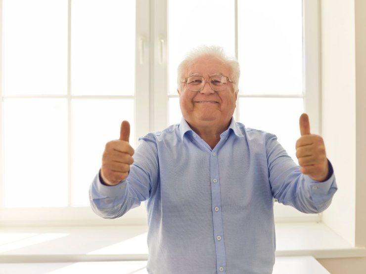 Pensionato con i pollici in su e sorridente