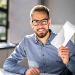 Uomo alla scrivania contento che sventola un biglietto