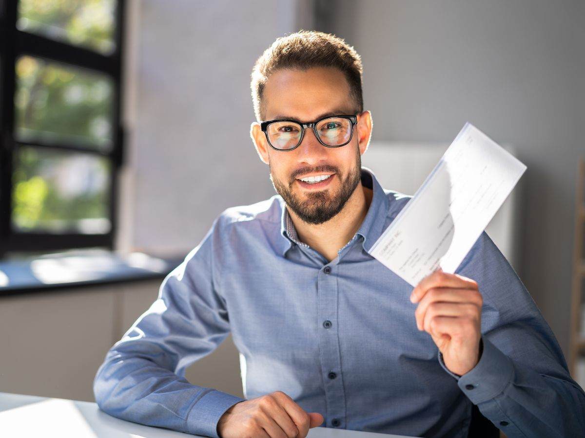 Uomo alla scrivania contento che sventola un biglietto