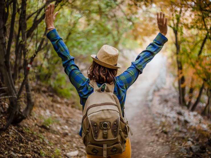 Donna che cammina con le mani alzate nel bosco