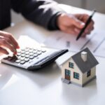 Casa, calcolatrice e uomo che fa dei calcoli