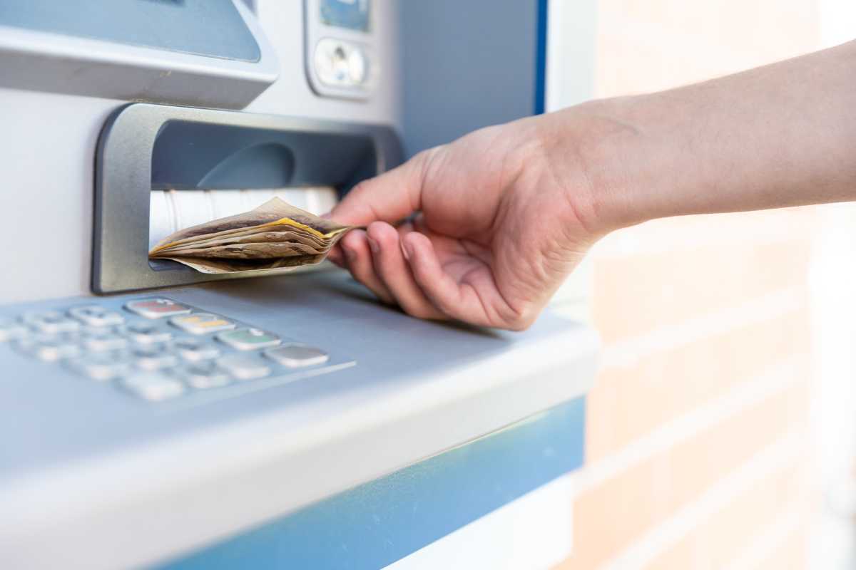 Mano ritira dei soldi al bancomat