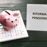 Salvadanaio porcellino sopra una calcolatrice e foglio con su scritto Riforma pensione