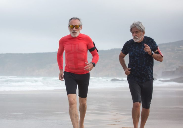 Uomini anziani che corrono in spiaggia