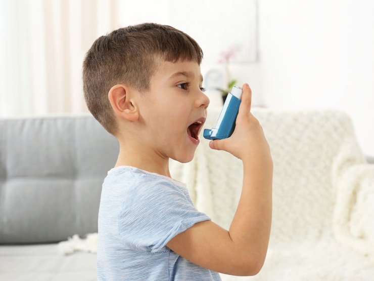 Bambino che spruzza in bocca uno spray per le allergie