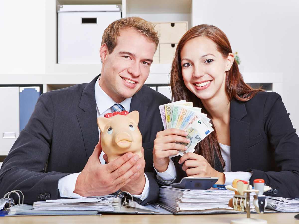 Uomo e donna contenti con soldi e salvadanaio in mano