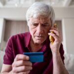 Uomo a telefono con una carta bancaria in mano
