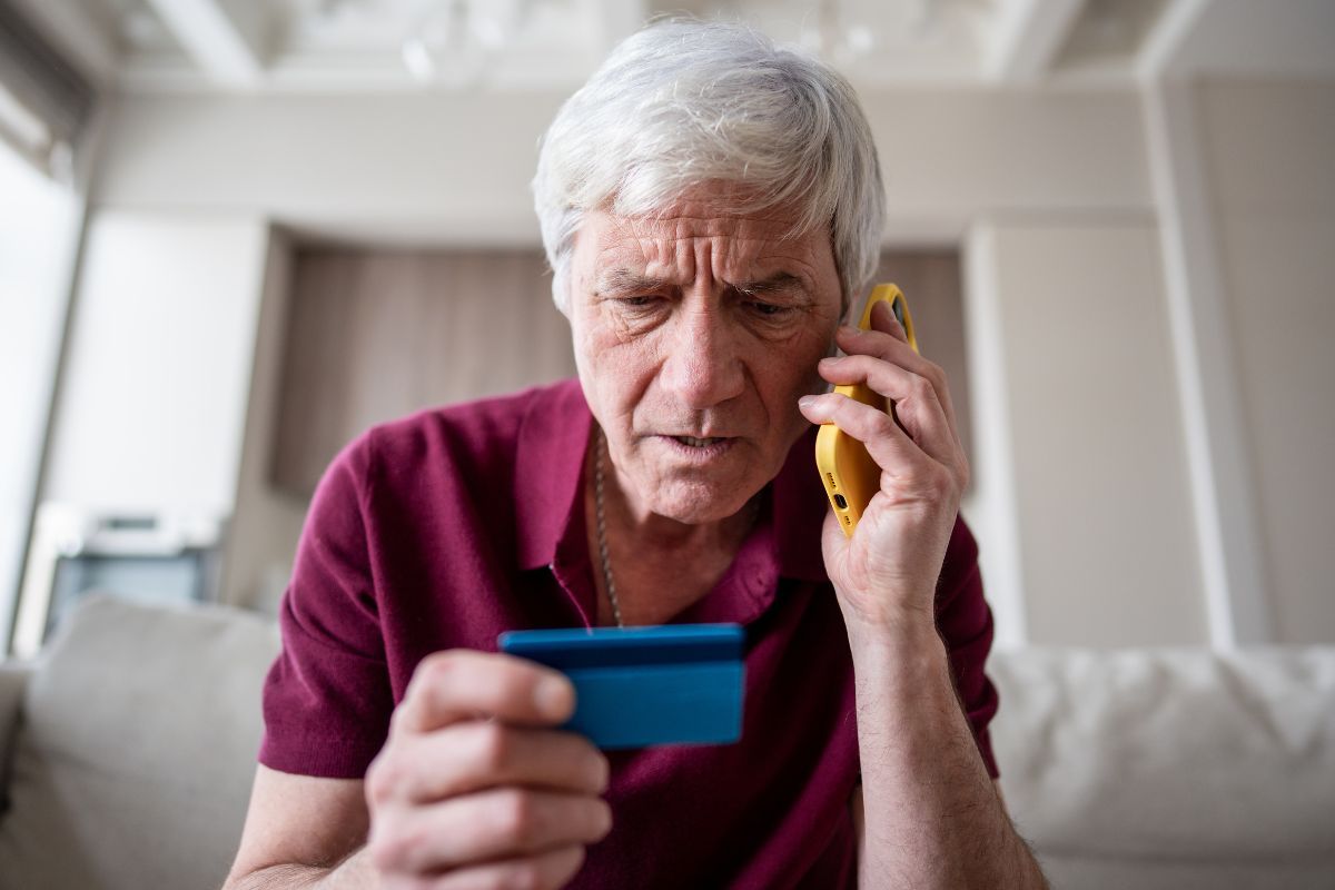 Uomo a telefono con una carta bancaria in mano