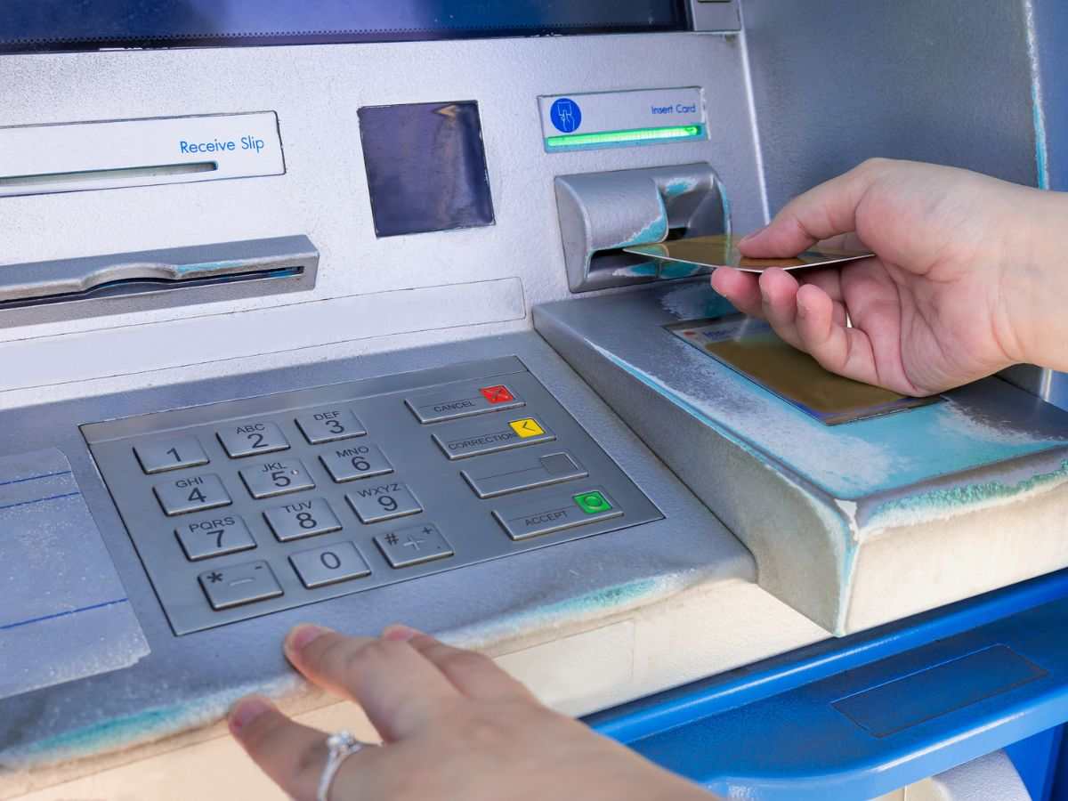 Bancomat e mani che inseriscono la scheda