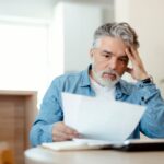 Uomo che legge un foglio ed è preoccupato