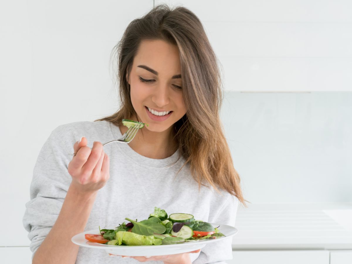 Donna sorridente che mangia verdure