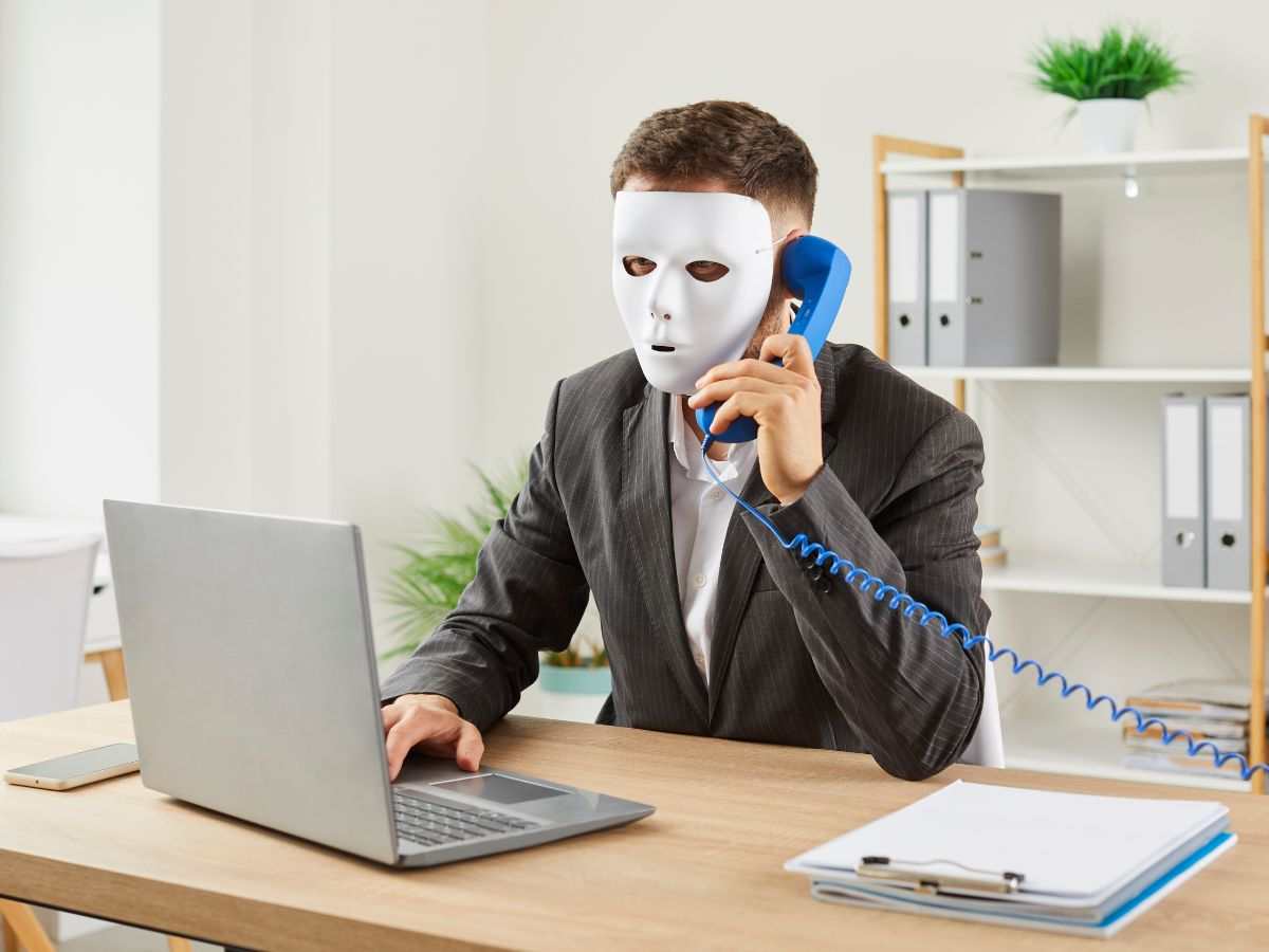 Uomo con maschera al telefono e con il pc