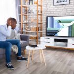 Persona guarda il televisore rotto