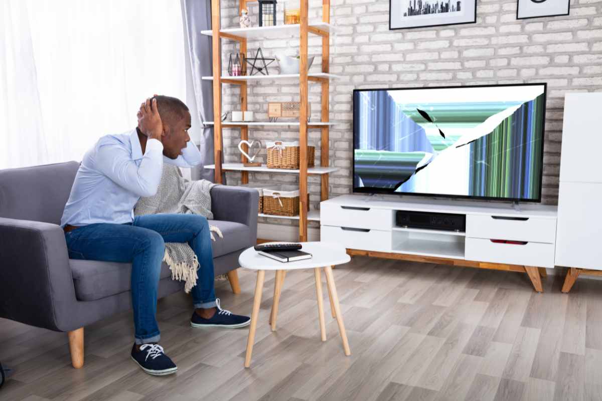Persona guarda il televisore rotto