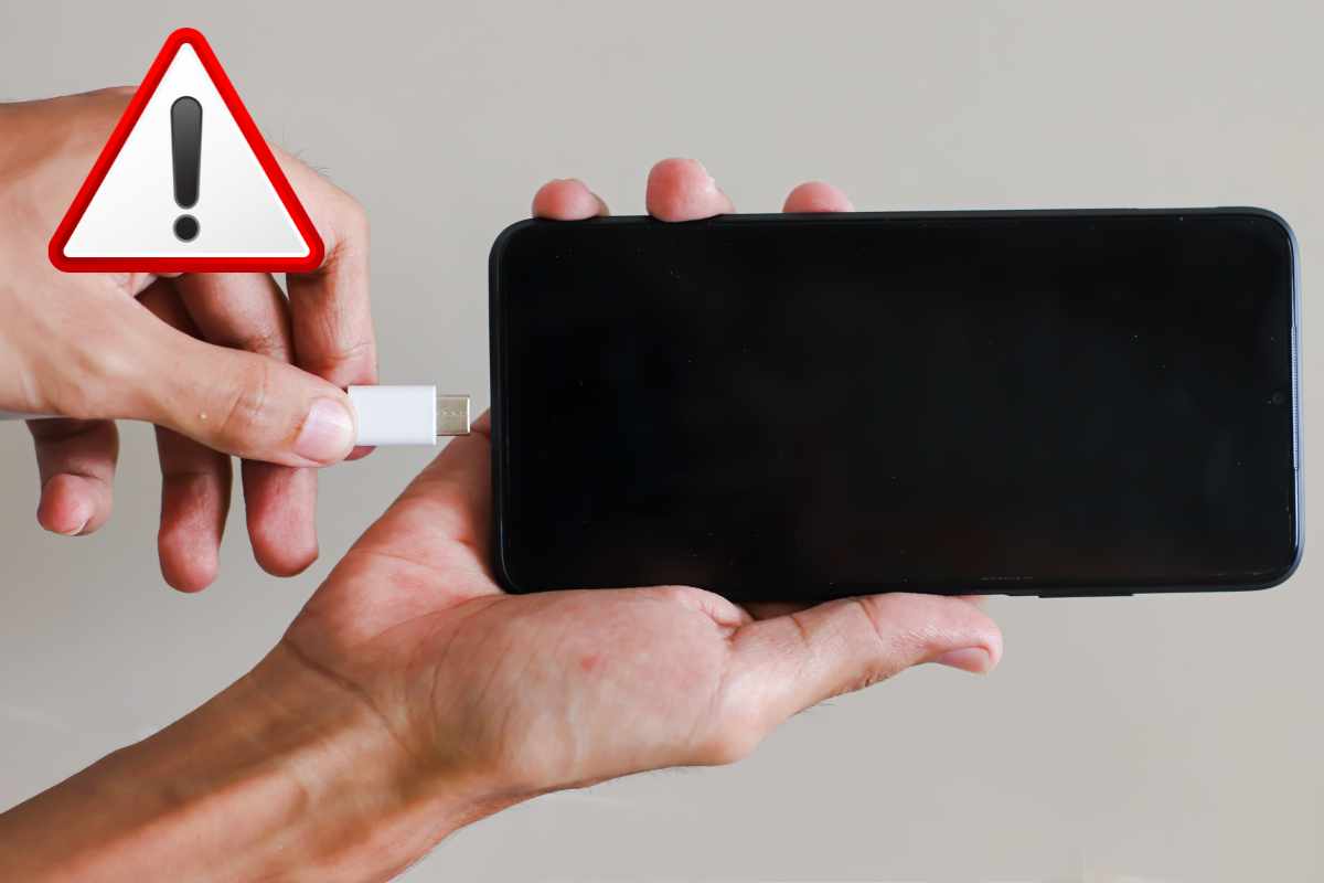 Mano inserisce il cavo di un caricabatterie all'interno di uno smartphone