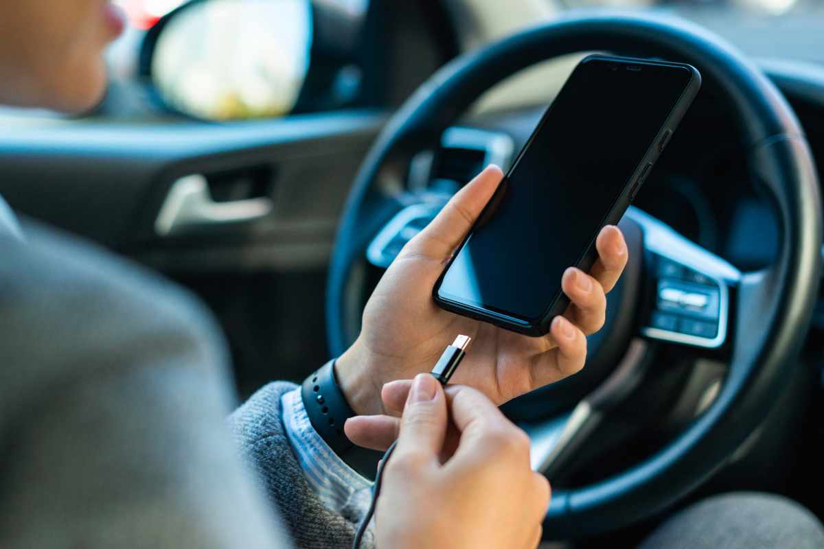 Persona carica il telefono in auto