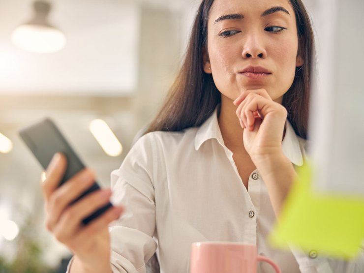 Donna dubbiosa con telefonino in mano