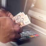 Persona che conta banconote da 50 euro davanti al bancomat