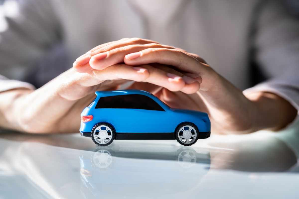 Persona che tiene tra le mani un automobile blu