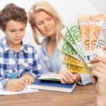 Bambino aiutato dalla mamma, mano con soldi