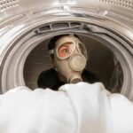 Persona con la maschera guarda dentro una lavatrice