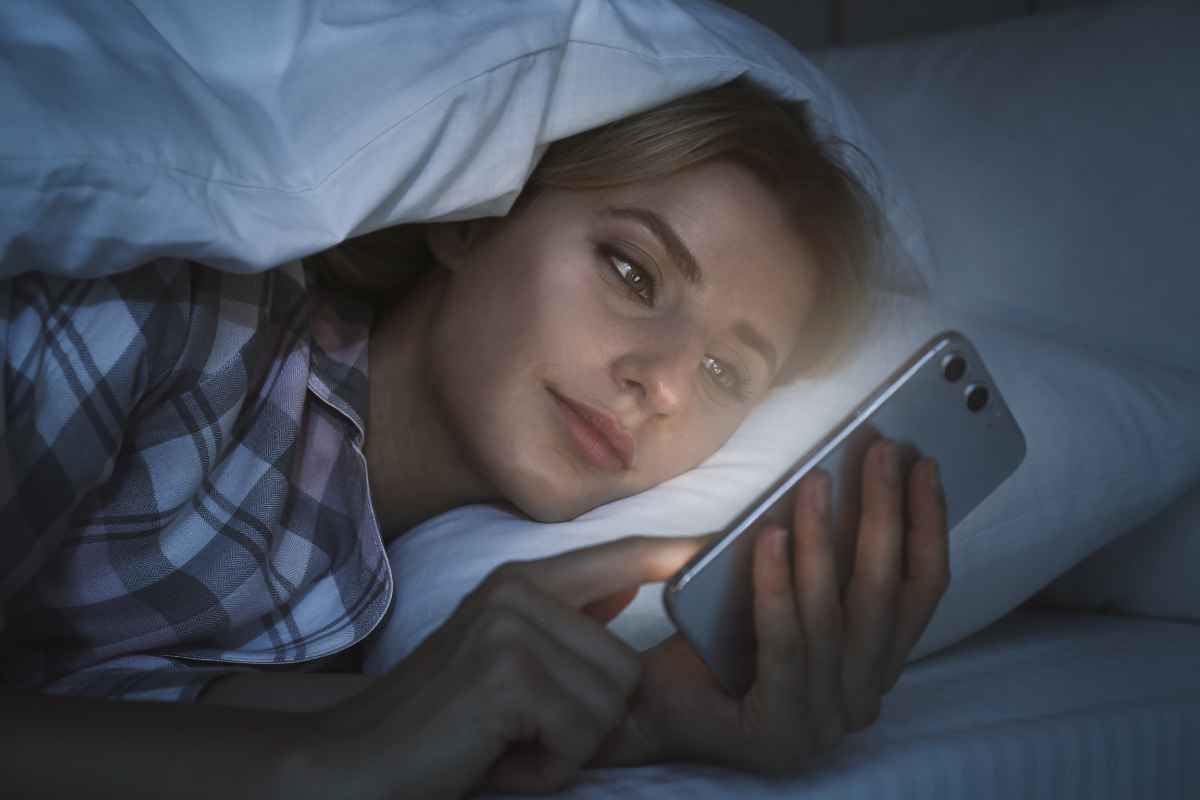 Donna con smartphone a letto