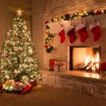 albero di natale illuminato in salotto accanto al caminetto