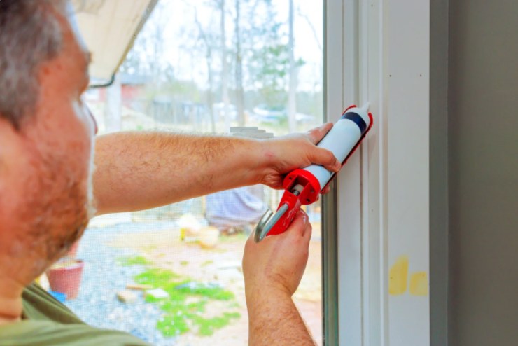 uomo che sigilla gli infissi di una finestra 