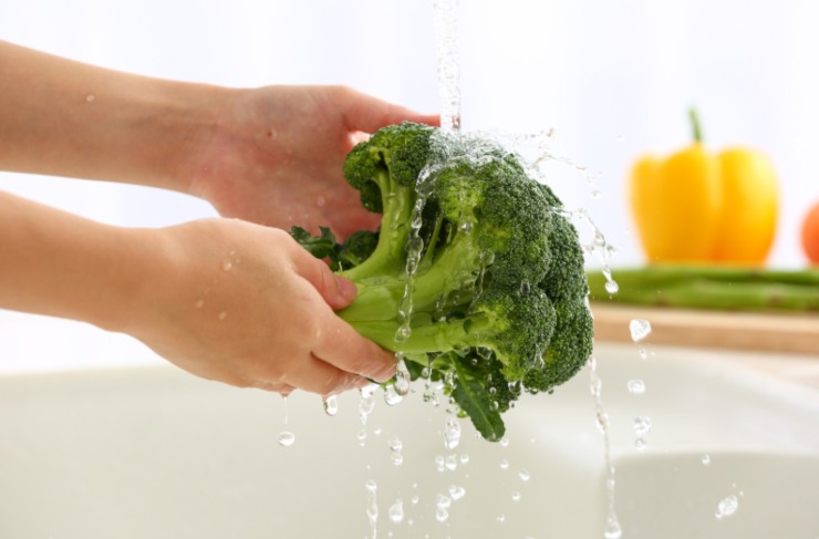 donna che lava i broccoli sotto l'acqua