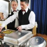 due camerieri portano il cibo nel buffet