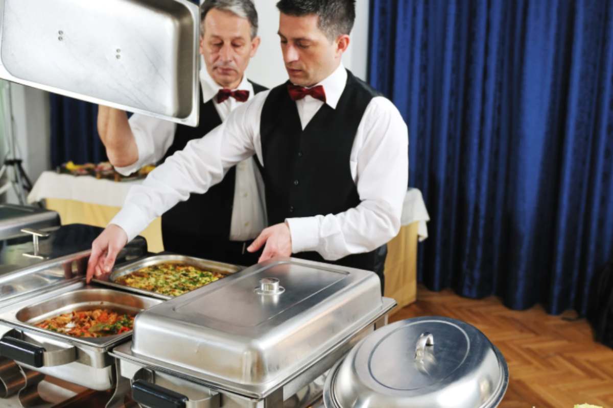 due camerieri portano il cibo nel buffet
