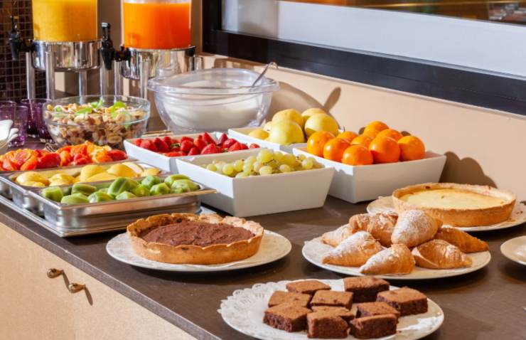 buffet della colazione con succhi di frutta, torte e brioche