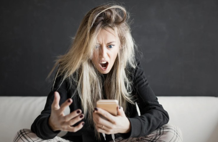 donna seduta furiosa mentre guarda il cellulare