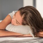 donna che dorme a pancia in giù con le mani sotto al cuscino