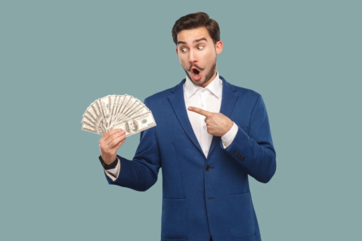 uomo con guardo stupito e con la bocca aperta che tiene in mano delle banconote