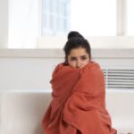 donna seduta sul divano con addosso una coperta