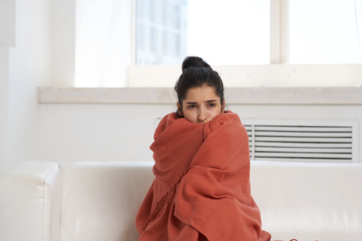 donna seduta sul divano con addosso una coperta