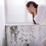 donna con le mani in testa mentre guarda la muffa sui muri