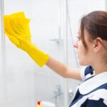 cameriera che pulisce la doccia con uno straccio