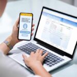 Persona al computer con il telefono in mano